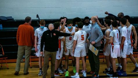 Members of the Boys’ Varsity Basketball team participate in a masked huddle during the 2020-2021 season.