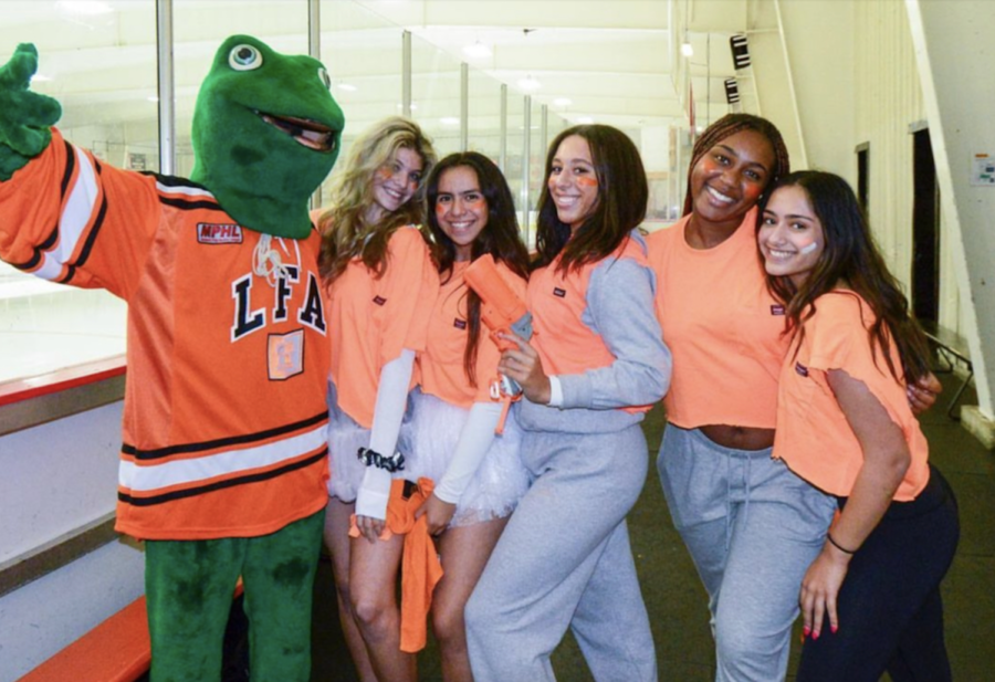Students pose for a photo at the Homecoming hockey game with the Caxy mascot.