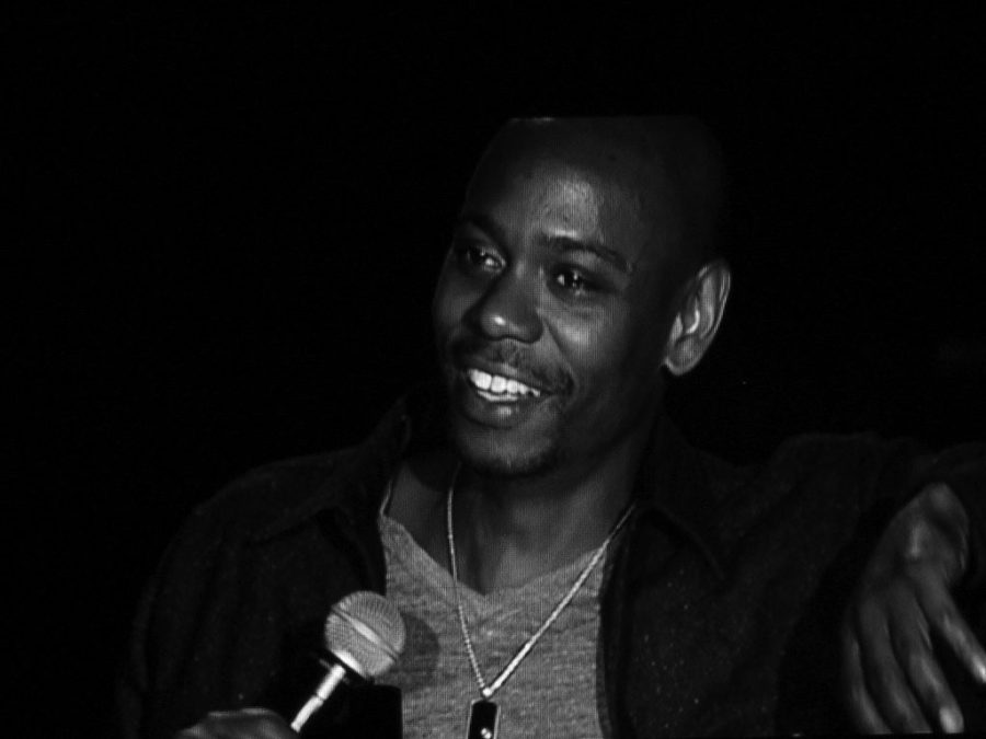 Comedian Chapelle—who is considered controversial—speaks into a microphone.