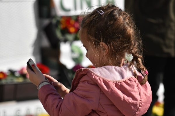 A young girl looks at a phone